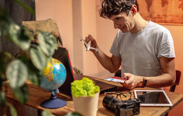 Fototapeta premium Man is buying airline tickets with a laptop online at home. Travel preparation and booking.