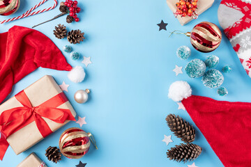 christmas background with decorations, frame made of gifts, candy canes, balls and trees on blue background, flat lay