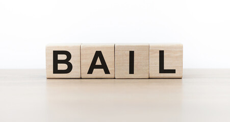 Four wooden cubes with letters Bail. Business marketing concept. Reflection of the caption on the mirrored gray surface of the table.