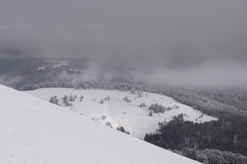 Fototapeta na wymiar Mountain valley covered with snow and clouds. Winter mountain landscape.