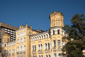 Fototapeta na wymiar Panoramic landscape view of vintage yellow brick building with the tower against blue sky in downtown of Kyiv. Neo-gothic style architecture. Kyiv, Ukraine