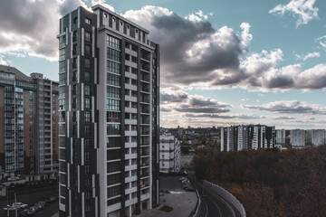 Modern residential buildings on uphill street with epic clouds, city architecture in evening autumn Kharkiv, Ukraine