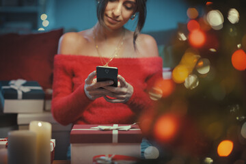 Woman sending Christmas wishes on her smartphone
