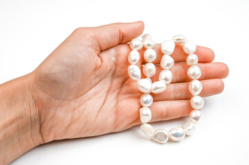Close up of woman hand with pearl necklace isolated on white. Hand with string of baroque pearls