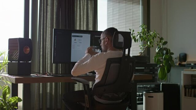 Handsome middle age man working on his computer at home and drink coffee. Home office concept