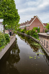 Obraz premium Road and brick houses by a canal in the Netherlands. Summer.
