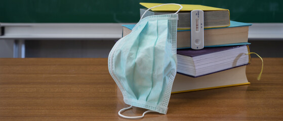 Closed school coronavirus background - Empty classroom due to COVID-19, books, face mask and...