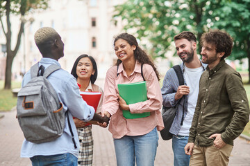 group of students meeting their friend with a handshake.