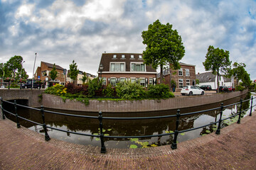 Road and brick houses by a canal in the Netherlands. Summer.