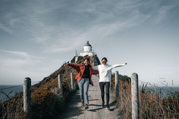 two caucasian girls running down the dirt road leading to the lighthouse on top of the big rock...
