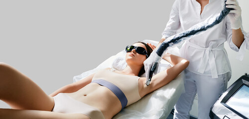 Laser armpit hair removal. Beautician removes hair on female armpit using a medical laser for epilation - obrazy, fototapety, plakaty