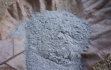 Ashes are placed on dry leaves for use as fertilizer or compost to nourish plants grown in gardens.