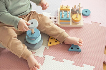 toddler baby sitting on carpet playing with colorful wooden stacking toy - 543155700