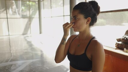 Latina yoga teacher explains alternate nostril breathing technique to her class - close up shot 