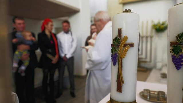 Candle focus: Baptism process in a catholic church with priest and newborn's family