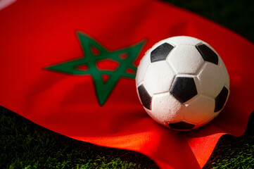 Morocco national football team. National Flag on green grass and soccer ball. Football wallpaper for Championship and Tournament in 2022. World international match.