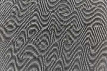 Surface and texture of a gray wave patterned concrete wall. Modern decoration and interior design in loft style. Background. Space for text. Selective focus.
