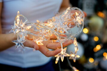 Women's hands hold a festive garland. The concept of holidays and gifts.