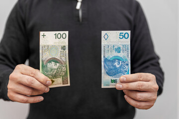The man holding two banknotes of PLN 100 and PLN 50 shows how much PLN 100 is now worth due to...