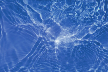 Defocus blurred transparent blue colored clear calm water surface texture with splashes and bubbles. Trendy abstract nature background. Water waves in sunlight with copy space. Blue watercolor shining