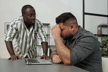 Angry African American businessman rebuking his colleague or subordinate of another ethnicity networking by workplace