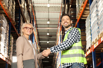 Obraz premium Happy manager shaking hands with worker in warehouse