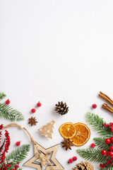 Christmas decorations concept. Top view vertical photo of wooden star ornament dried orange slices cinnamon sticks mistletoe berries pine cone fir branches on isolated white background with copyspace