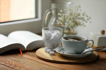 Obraz na płótnie Canvas Tray with cup of freshly brewed tea and sugar cubes on wooden table, space for text