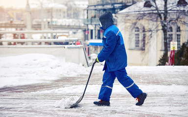 Man with sleigh shovel move snow from sidewalk, worker with handle shovel scoop up snow and slide...
