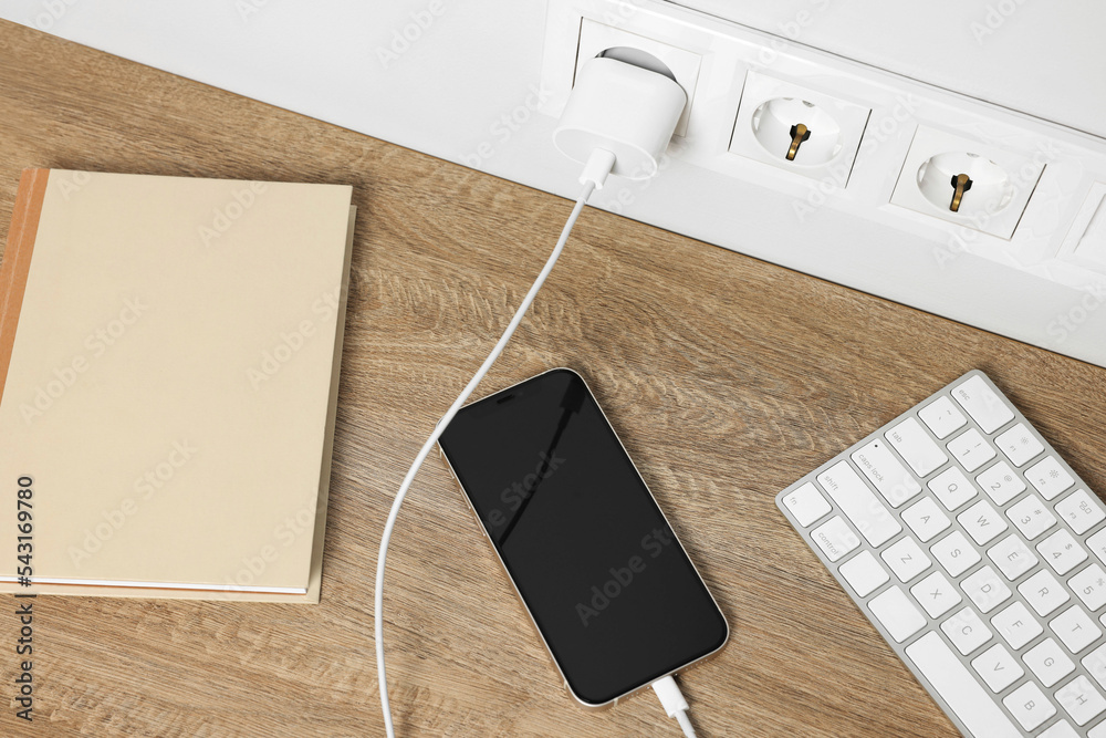 Wall mural modern smartphone charging on wooden table, above view