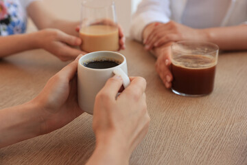 Woman holding cup of coffee spending time with friends in cafe, closeup