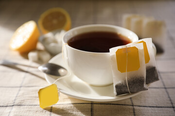 Tea bags near cup of hot drink on table, closeup