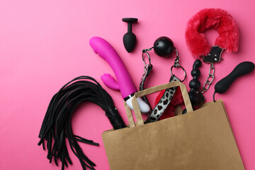 Paper shopping bag with different sex toys on pink background, flat lay - obrazy, fototapety, plakaty
