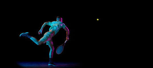 Studio shot of professional tennis player playing tennis isolated over dark background in neon light. Concept of motion, speed, professional sport.