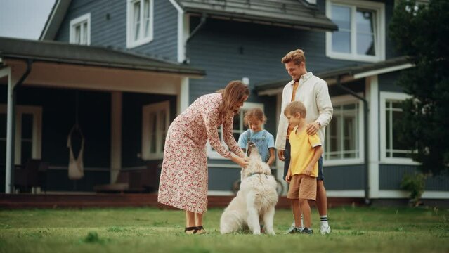 Portrait of a Cheerful Family Couple with Kids, Playing and Petting a Beautiful White Golden Retriever Dog. Happy Successful People Standing on a Lawn in Their Front Yard in Front of the House.