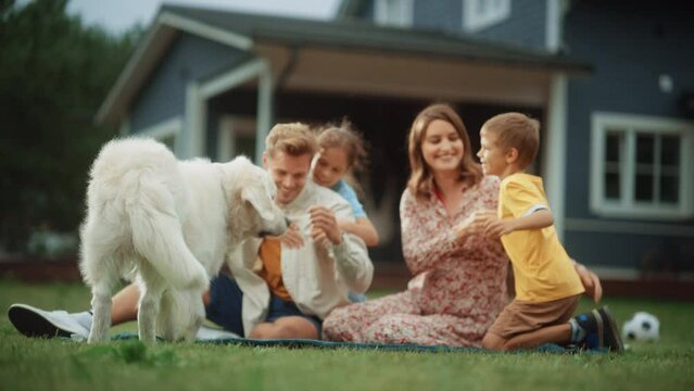 Portrait of a Cheerful Family Couple with Kids, Playing and Petting a Beautiful White Golden Retriever Dog. Happy Successful People Sitting on a Lawn in Their Front Yard in Front of the House.