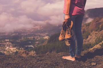 Concept back view of female people barefoot with broken shoes on hand admiring landscape panorama....