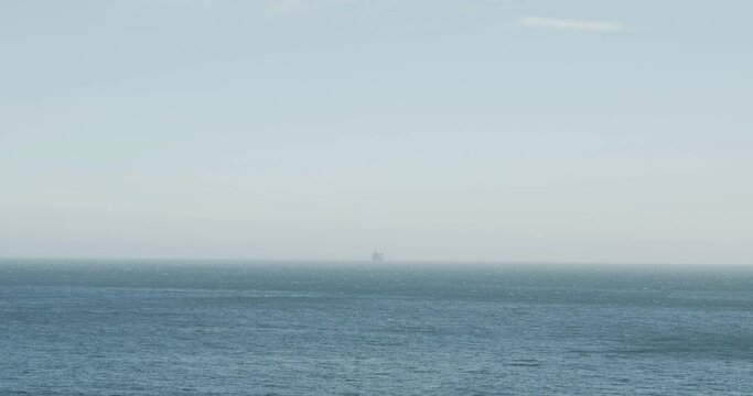 Wide Shot Go The Ocean With An Oil Rig On The Horizon.