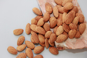small grains of natural brown almonds on a marble stone on a gray background