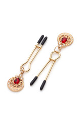 Close-up shot of gold tweezer nipple clamps with a pendant and rubber tips. Beaded nipple clamps...