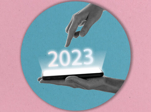 Finger presses button 2023 on smartphone virtual interface with copy space for text. New year concept. Modern art collage