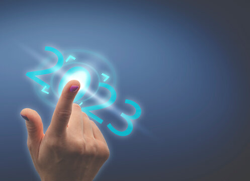 Finger pressing  2023 button on virtual interface on blue background with copy space for text. Concept of new year.