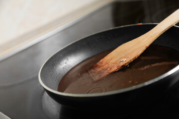 Frying pan with spatula and used cooking oil on stove, closeup