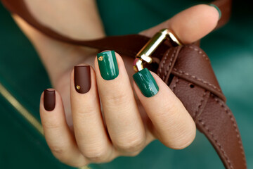 Green brown manicure on short nails with golden dots.