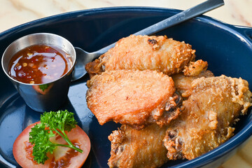 homemade deep fried chicken wings with dipping chilli sauce in navy plate