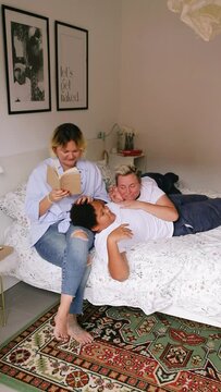 two mothers and child laying on the bed and reading in voce