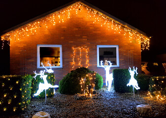 Danish home decorated with christmas lights and ornaments outside the house and in the garden in...