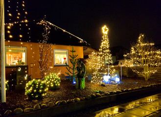 Danish home decorated with christmas lights and ornaments outside the house and in the garden in...