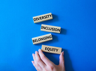Diversity Inclusion Belonging Equity symbol. Concept words Diversity Inclusion Belonging Equity on wooden blocks. Businessman hand. Beautiful blue background. Business concept. Copy space.