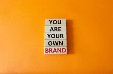 You are your own brand symbol. Wooden blocks with words You are your own brand. Beautiful orange background. Business and You are your own brand concept. Copy space.
